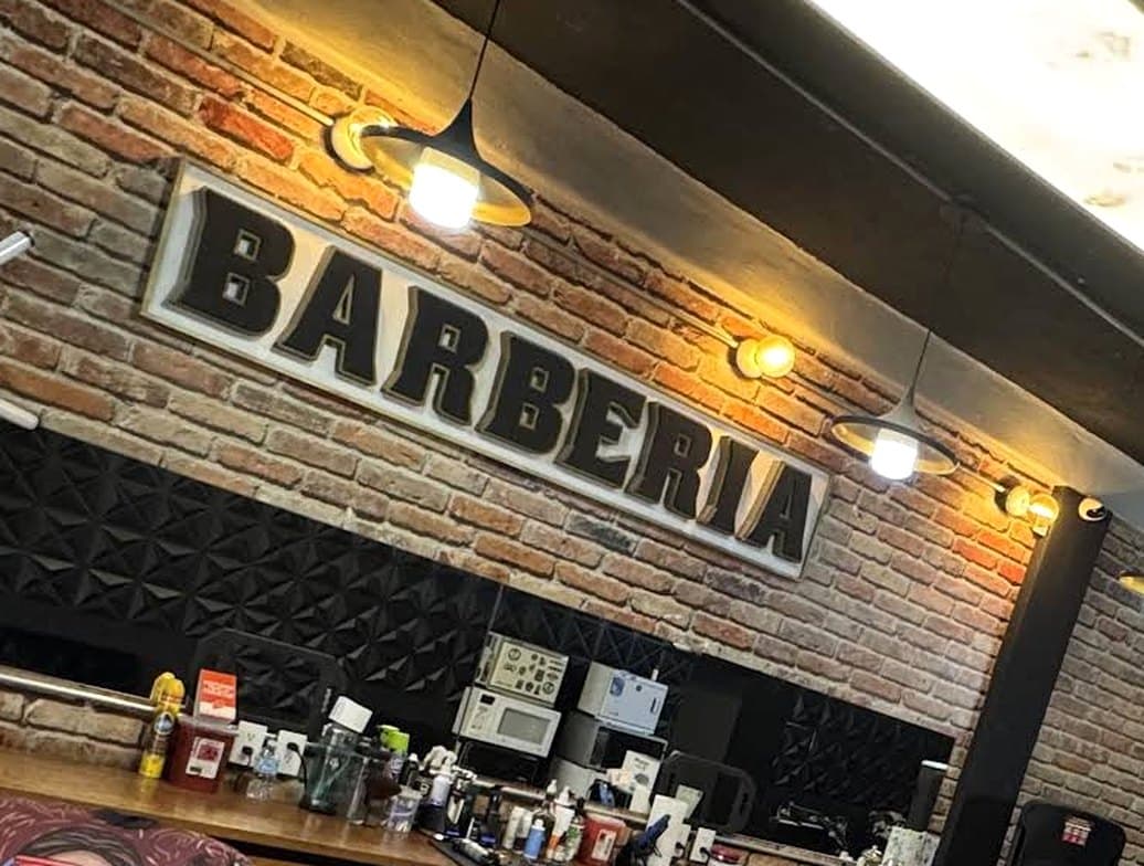 Letrero de la barbería sobre muro de ladrillo con lámparas cálidas